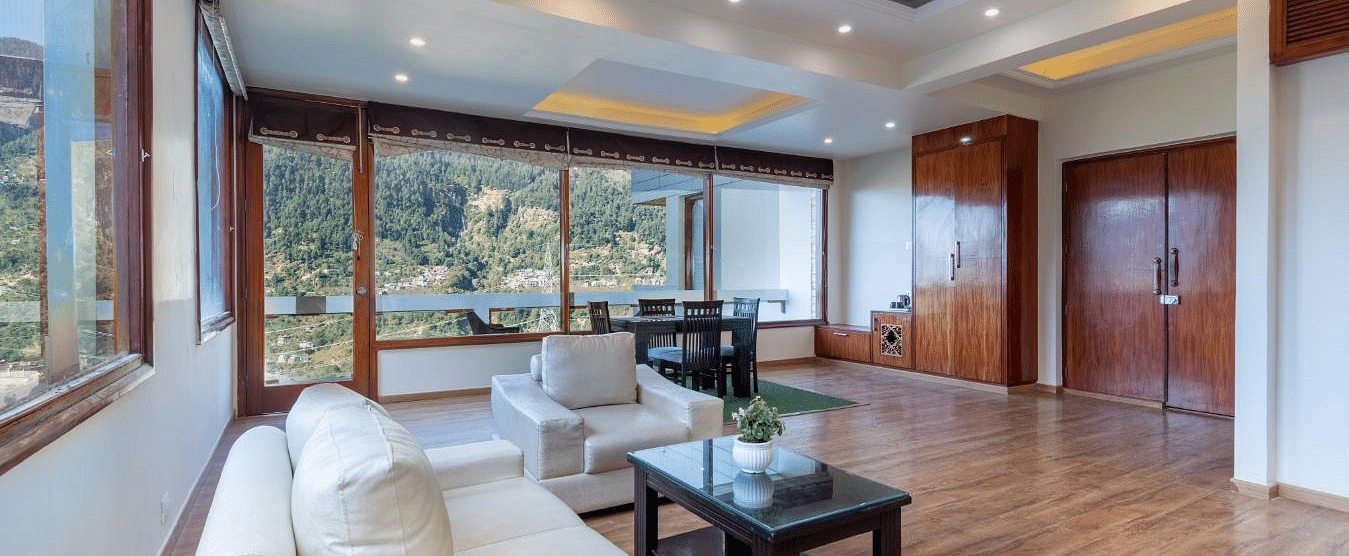 Shot of the seating area at the suite featuring white couches and a expansive window | DLS Serenity Resort and Spa